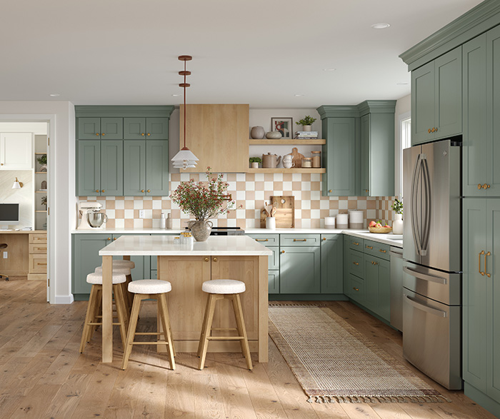 Modern farmhouse kitchen featuring sage green cabinets, a large wood island with white countertop, stainless steel appliances, and natural wood flooring.