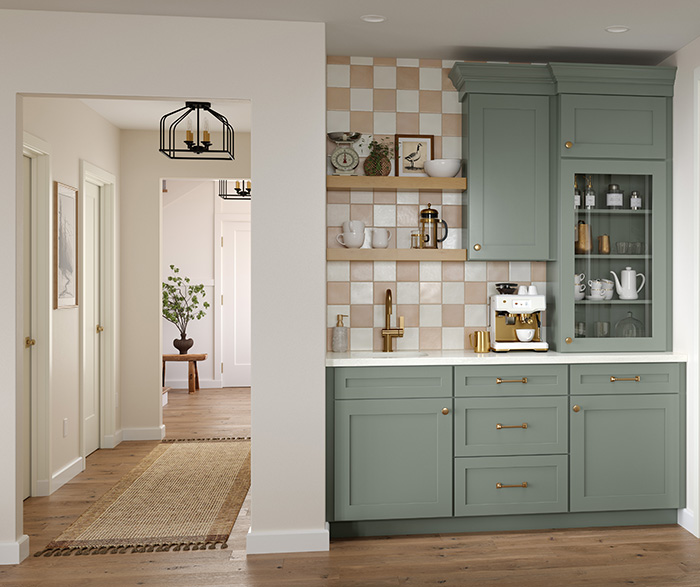 Sage green kitchen cabinets with glass display door, coffee station setup, open shelving, and checkered backsplash in a modern farmhouse kitchen.